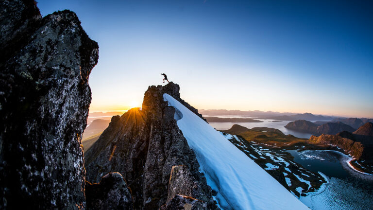 elementos esenciales senderismo: persona en la cima de una montaña nevada