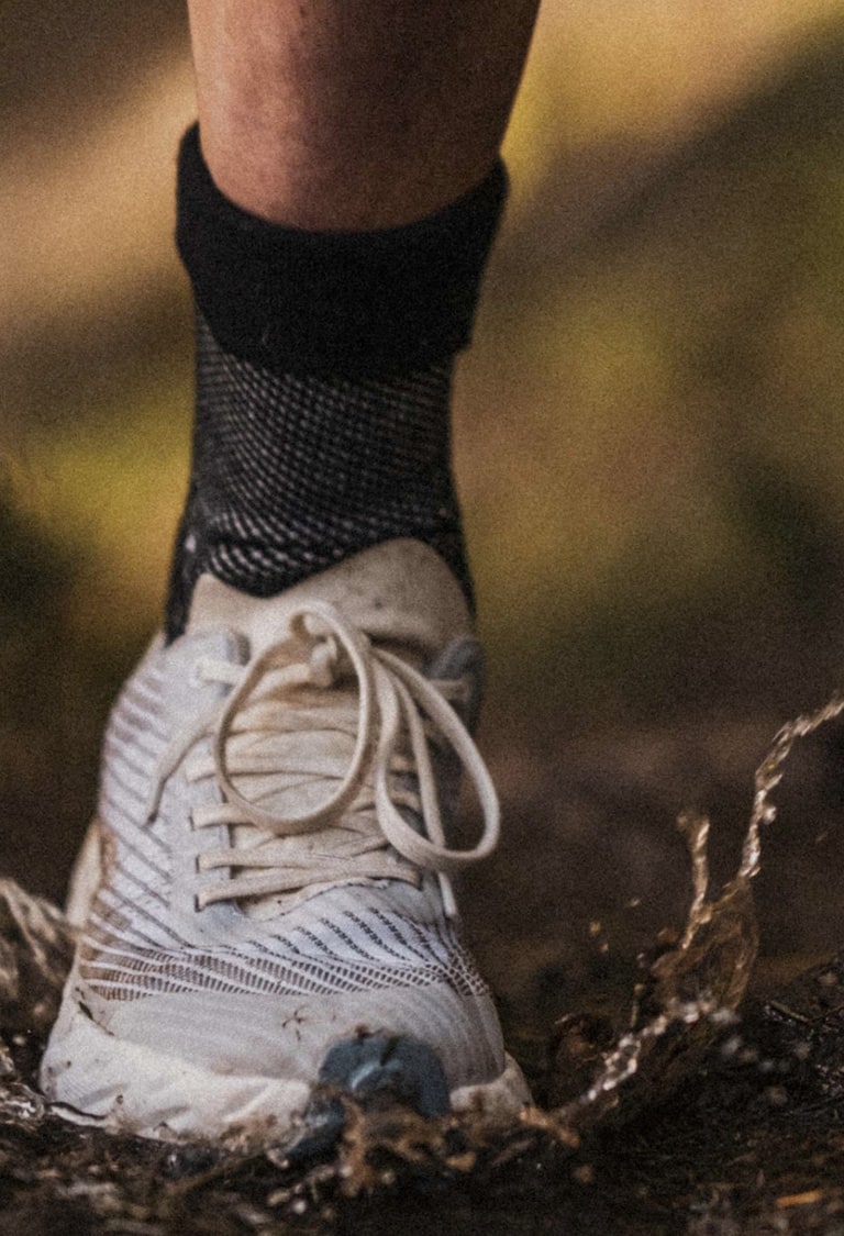Primer plano de una zapatilla de trail running de mujer que se hunde en  suelos blandos en forest trail